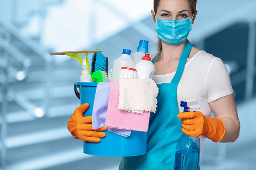 Cleaning lady with tool in cleaning in mask on a blurred background.