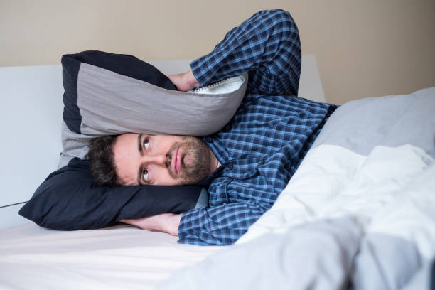 Man bothered by neighbor noise trying to sleep