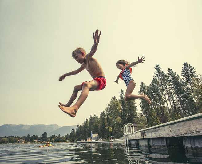 Kids jumping off the dock into a beautiful mountain lake
