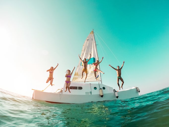 Happy crazy friends diving from sailing boat into the sea - Young people jumping inside ocean in summer vacation